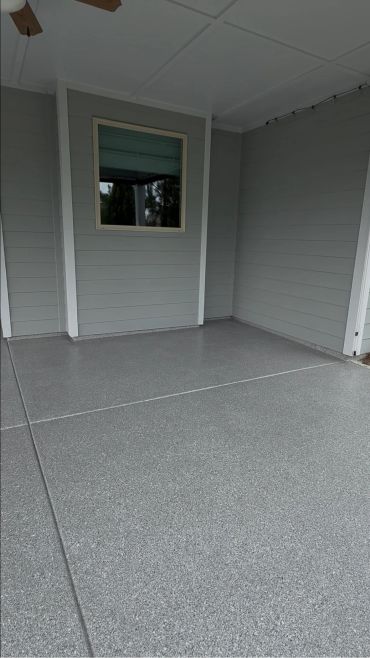 Empty covered patio with gray textured floor and window.