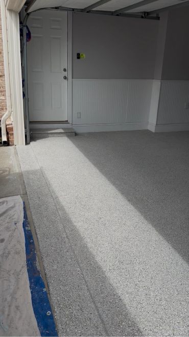 Clean and freshly coated garage floor with a white door at the back.