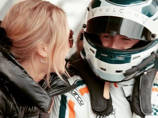 Image of Phil Quaife in race helment and race suit smiling at wife Lizzie Quaife