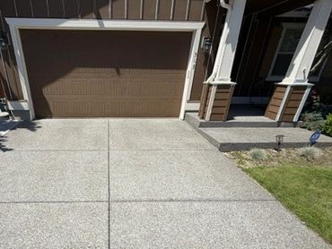 Clean concrete driveway leading to a brown garage door.