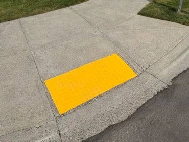 Concrete sidewalk with a yellow tactile warning surface.