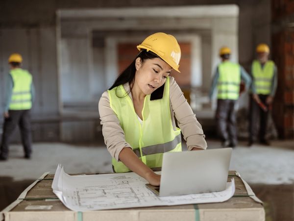 Woman construction manager on the phone, working on a laptop.