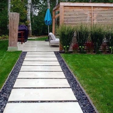 Modern garden pathway with large stone slabs and green lawn.