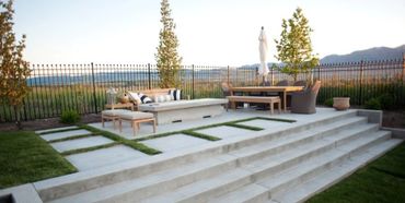 Modern outdoor patio with seating, dining area, and scenic mountain view.