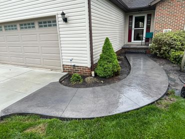 Curved concrete walkway leading to a house entrance beside a garage.