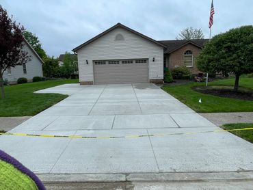 Newly poured concrete driveway in front of a suburban garage.