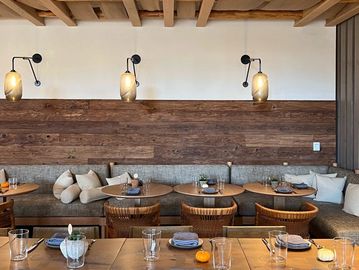 Cozy wooden dining area with modern lighting and neatly set tables.