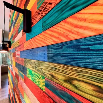Colorful wooden panel wall with hanging light fixtures creating a vibrant interior.