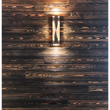 Modern wall sconce light on dark wood paneling.