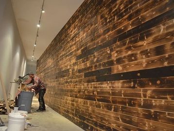 Man working on wood paneling in a long hallway with tools.