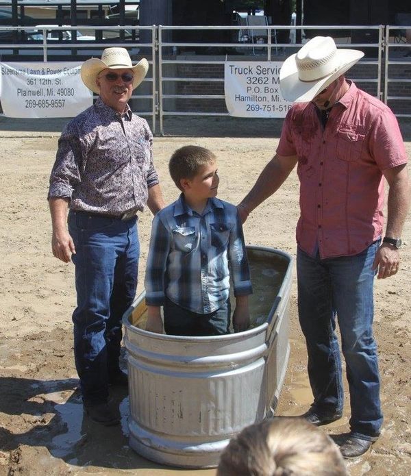 Boy standing in a tub with two men in cowboy hats.