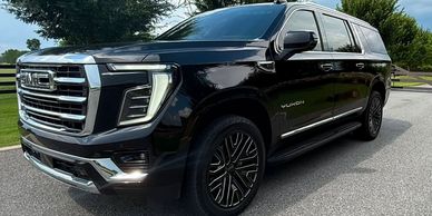 Black GMC Yukon SUV parked on road.
