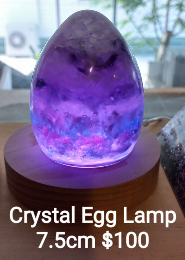 Purple crystal egg lamp glowing on wooden base.