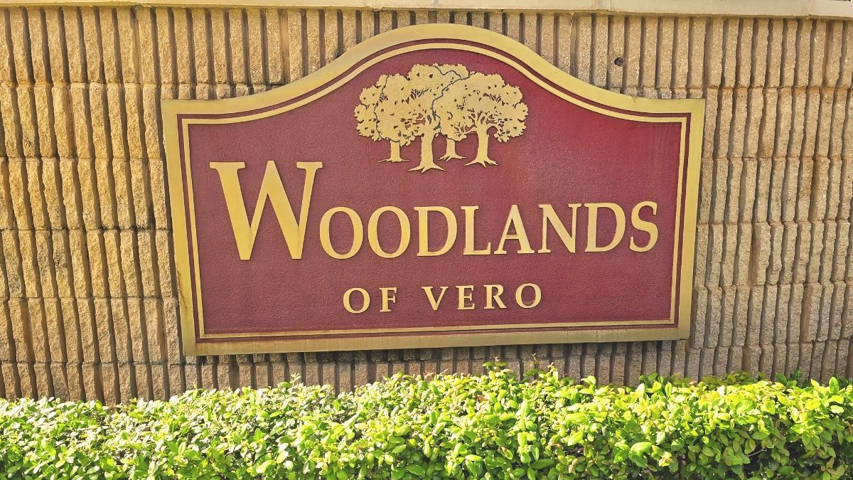 Entrance sign for Woodlands of Vero residential community with tree logo.