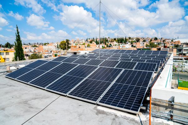 Solar panels installed on a rooftop under a partly cloudy sky.