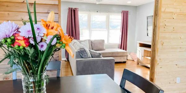 Living room with flowers on table and gray sofa.