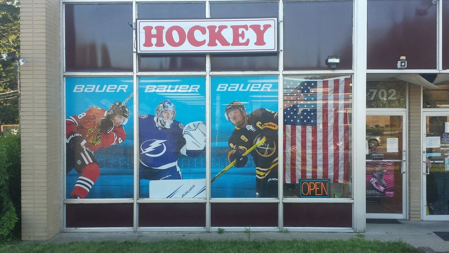 Storefront. Hockey sign. 3 windows have hockey player posters. one has an American flag.