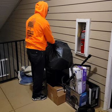 Man collecting trash from apartment breezeway for disposal in Mableton, Ga