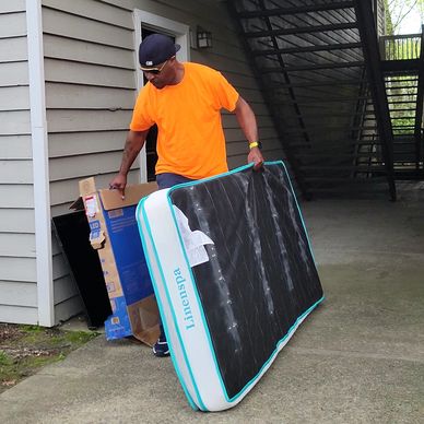 Man performing apartment Clean-Out in Lithia Springs, Ga by carrying twin mattress and tv to truck