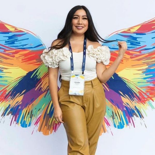 Woman posing with colorful painted wings background, smiling.