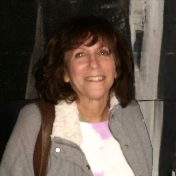 Smiling woman in a gray jacket with a white fur collar.