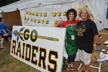 Harding "Go Raider" sign with two volunteers for the school