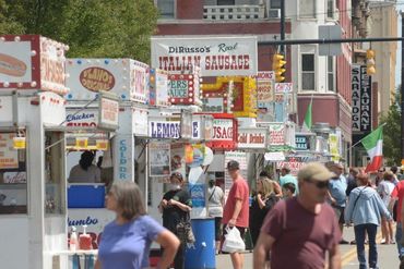 People walking down the street deciding which vendor trailer to eat at.