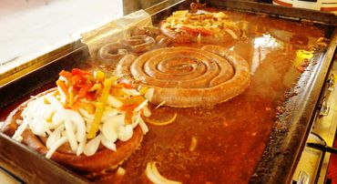 Coiled up Italian sausage on the grill waiting to be cut up and served.