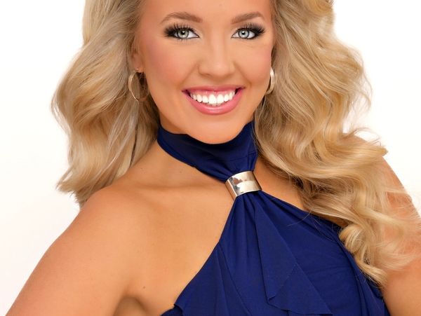 Smiling woman in blue dress with long blonde hair.