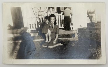 Mother and child sitting in the grass in front yard 1946.