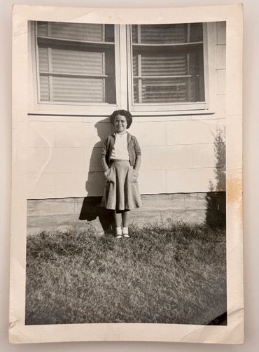 A young girl is standing in front of a house