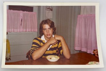 A teenage boy sitting in a kitchen.