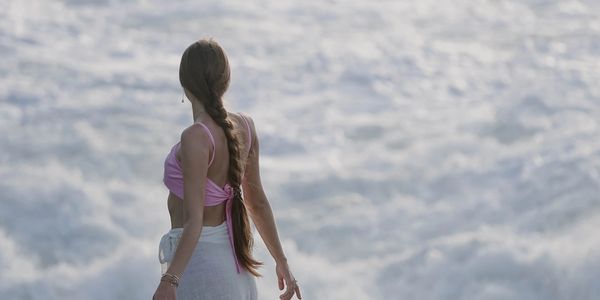 Woman with long braid standing by the sea.