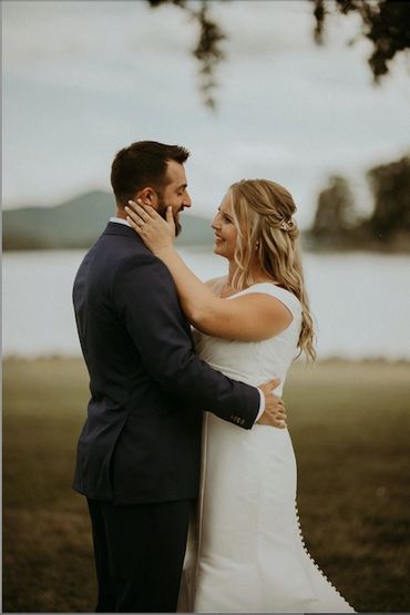 a bride and groom embracing in front of a lake