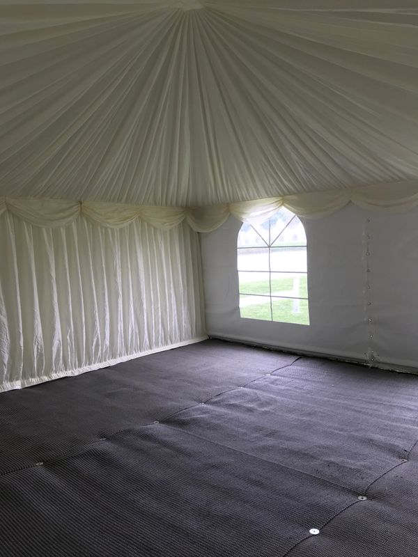 Empty white event tent with a window and dark flooring.