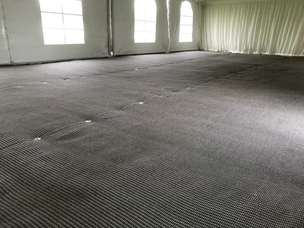 Empty large tent with textured floor covering and translucent windows.