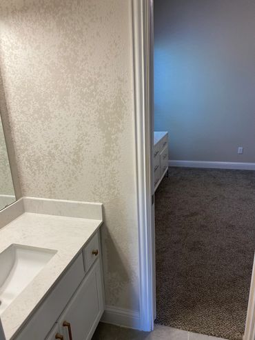 View of a bathroom vanity next to a carpeted bedroom.