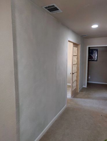 A hallway with beige carpeting and walls, featuring a door with glass panels.