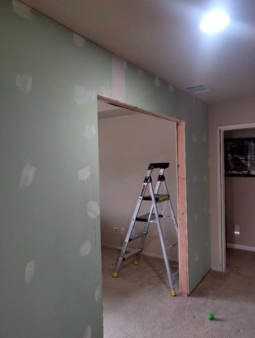 Room under renovation with a ladder and partially finished drywall.