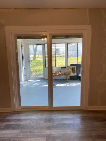 Newly installed sliding glass door leading to a screened porch and backyard.