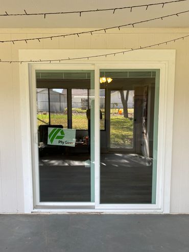 New sliding glass door installed with Ply Gem label visible, string lights above.