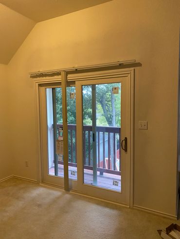 Sliding glass door leading to a balcony with a view of trees.