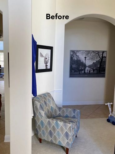Cozy corner with patterned armchair and black-and-white wall art before makeover.