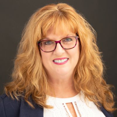 Smiling woman with glasses and curly hair.