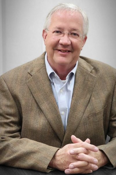 Smiling man in glasses and brown blazer.