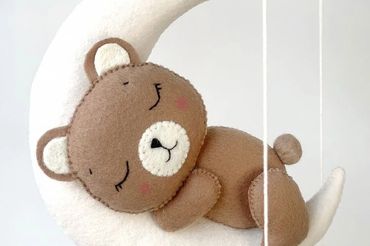 crib mobile featuring teddy bear sleeping on the moon