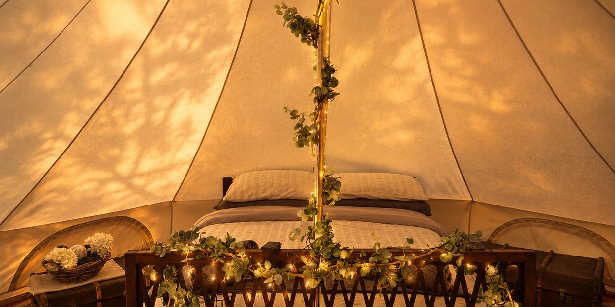 Cozy tent bedroom with warm lighting and greenery decorations.