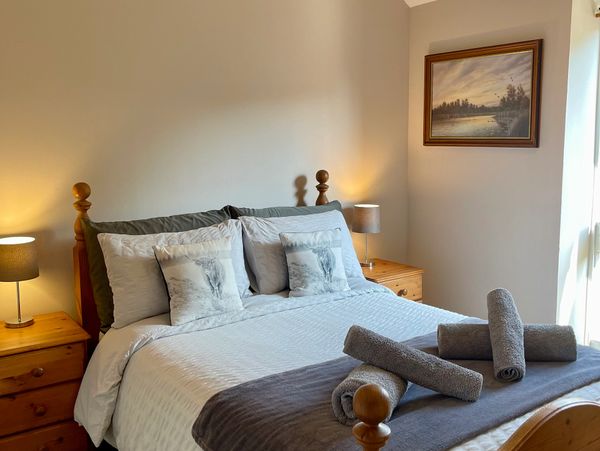 Cozy bedroom with a neatly made bed and rolled towels.