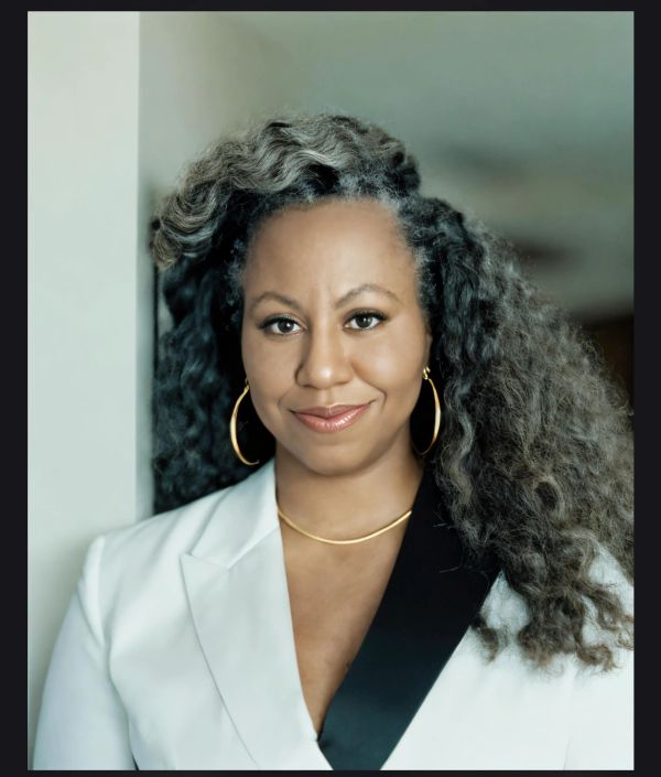 Confident woman with curly hair in a white blazer.