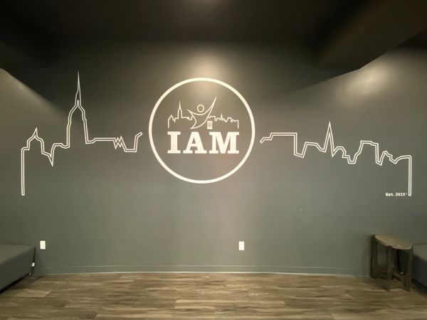 Wall mural with 'IAM' and city skyline.